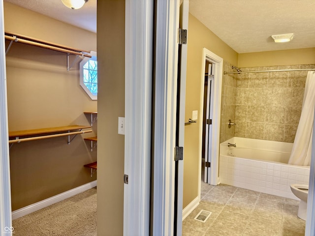 bathroom featuring tile patterned floors, shower / tub combo with curtain, a textured ceiling, and toilet