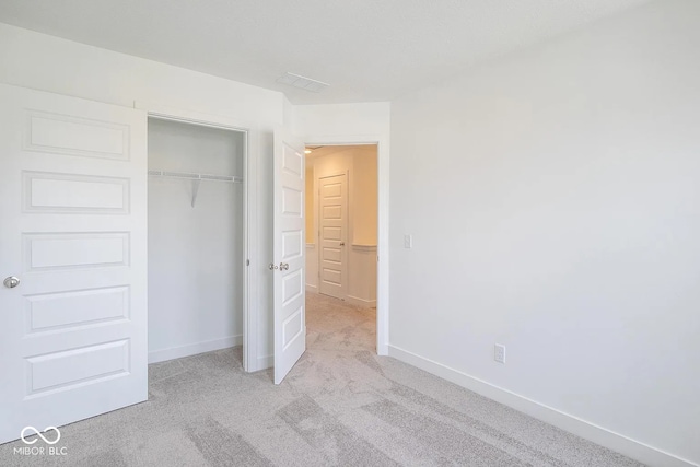 unfurnished bedroom featuring light colored carpet and a closet