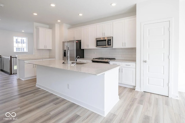 kitchen featuring stainless steel appliances, white cabinetry, and an island with sink