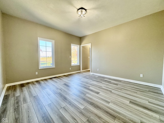 spare room featuring a textured ceiling and light hardwood / wood-style flooring