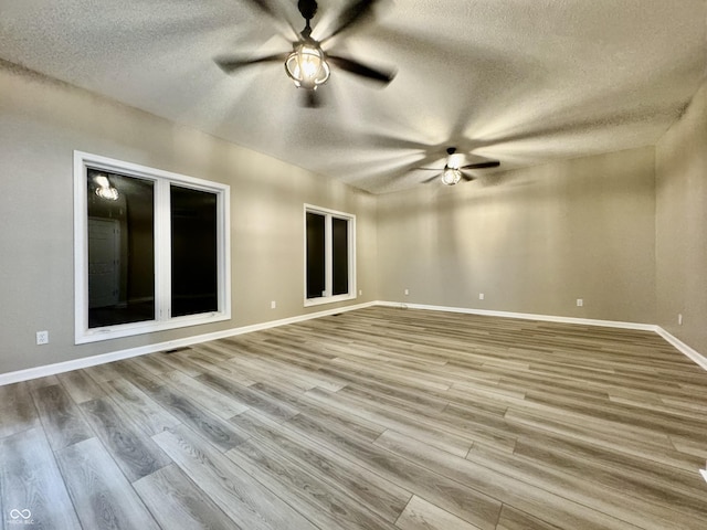 spare room featuring ceiling fan, light hardwood / wood-style floors, and a textured ceiling