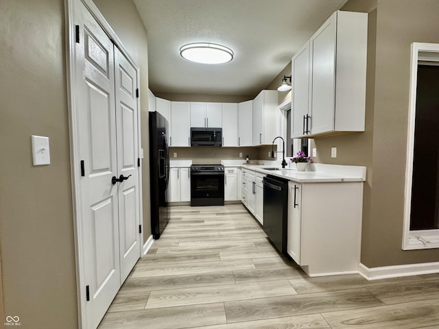 kitchen with white cabinets, sink, light hardwood / wood-style flooring, and black appliances