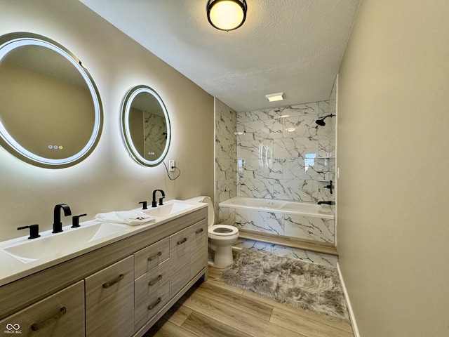 full bathroom featuring vanity, hardwood / wood-style flooring, tiled shower / bath combo, toilet, and a textured ceiling