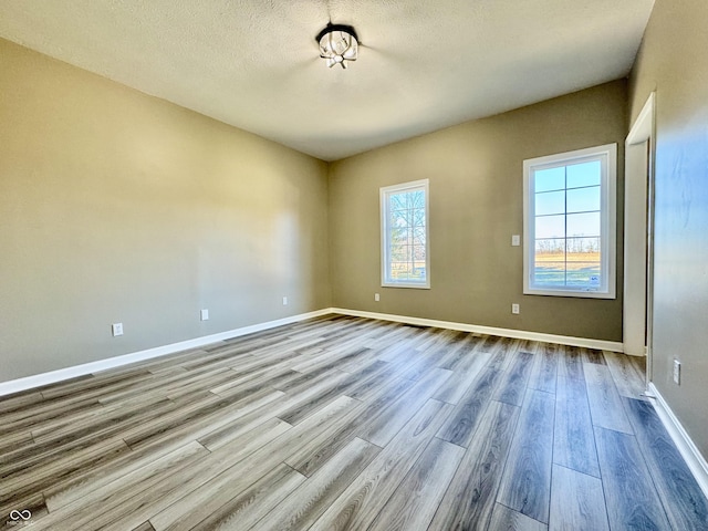 unfurnished room featuring a textured ceiling and light wood-type flooring