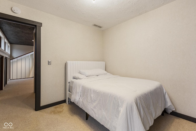 bedroom with a textured ceiling and light carpet