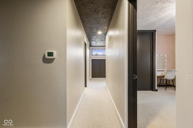 corridor with light colored carpet and a textured ceiling