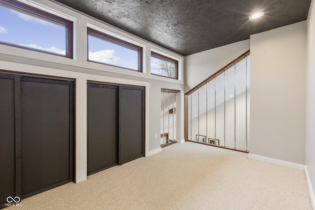 foyer featuring light carpet, a textured ceiling, and vaulted ceiling