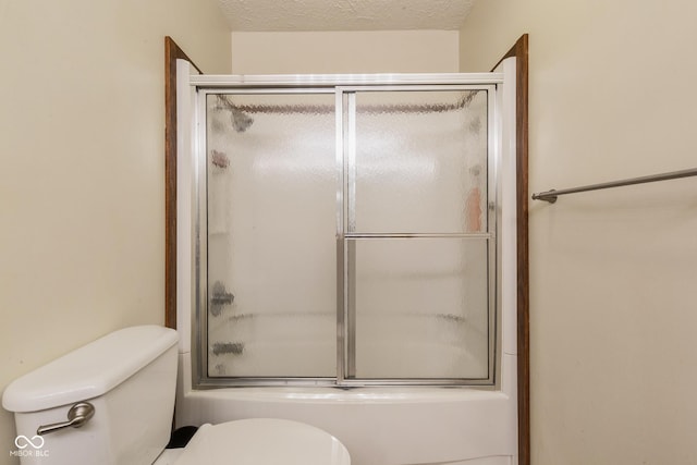 bathroom featuring enclosed tub / shower combo, a textured ceiling, and toilet