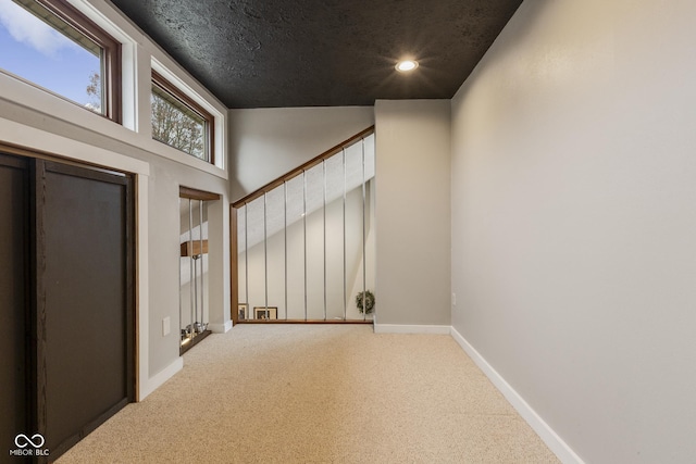 interior space with carpet flooring, a textured ceiling, and a high ceiling