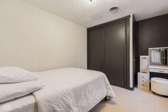 bedroom with a textured ceiling and light colored carpet