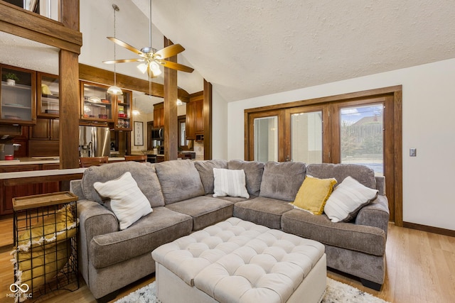 living room featuring ceiling fan, high vaulted ceiling, light hardwood / wood-style floors, and a textured ceiling