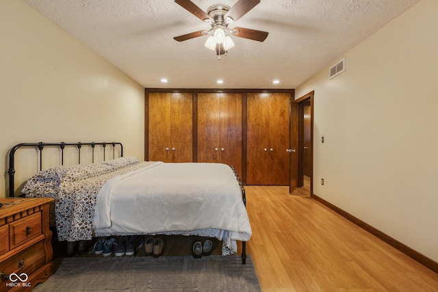 bedroom featuring ceiling fan, light wood-type flooring, a textured ceiling, and a closet