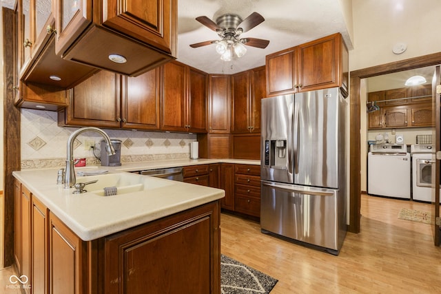 kitchen featuring sink, ceiling fan, light wood-type flooring, stainless steel appliances, and washing machine and clothes dryer