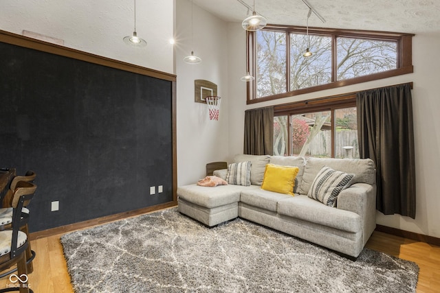 living room with a towering ceiling, a textured ceiling, and hardwood / wood-style flooring