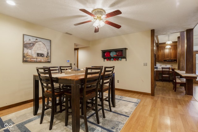 dining room featuring light wood-type flooring, a textured ceiling, and ceiling fan