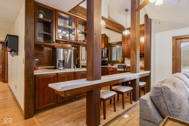 bar with appliances with stainless steel finishes, light wood-type flooring, vaulted ceiling, a healthy amount of sunlight, and pendant lighting