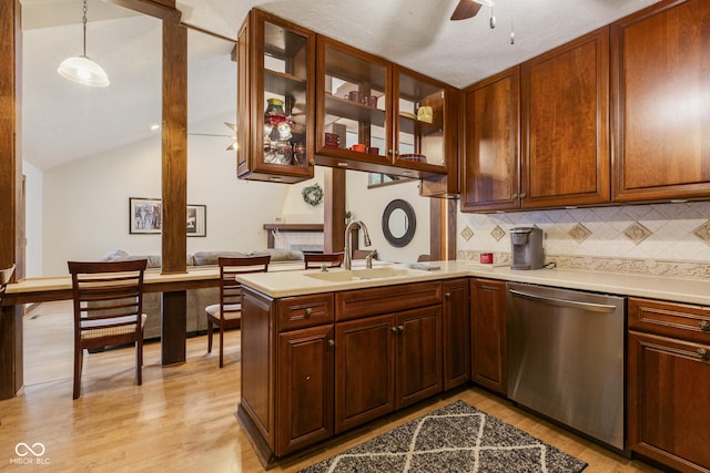 kitchen with sink, hanging light fixtures, stainless steel dishwasher, light wood-type flooring, and kitchen peninsula