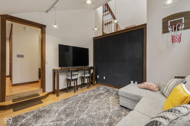 living room with a textured ceiling, hardwood / wood-style floors, and vaulted ceiling