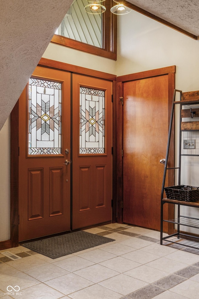 entrance foyer featuring a textured ceiling, light tile patterned flooring, and vaulted ceiling