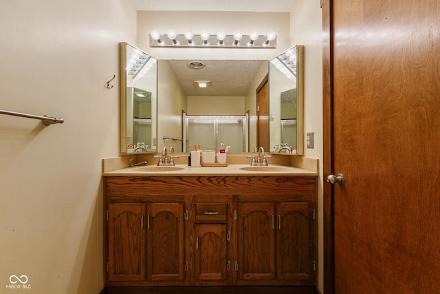 bathroom with vanity, a textured ceiling, and walk in shower