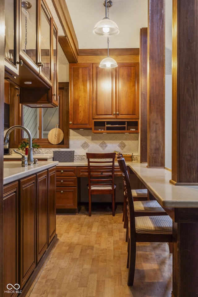 kitchen featuring tasteful backsplash, sink, light hardwood / wood-style floors, and decorative light fixtures