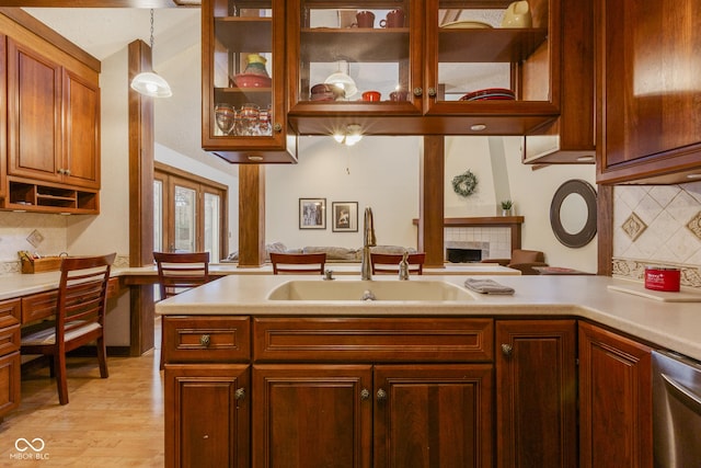 kitchen with tasteful backsplash, sink, hanging light fixtures, and light hardwood / wood-style flooring