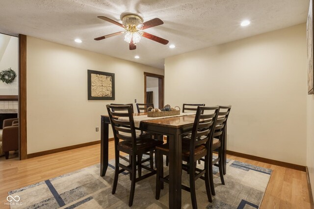 dining room with ceiling fan, light wood-type flooring, and a textured ceiling