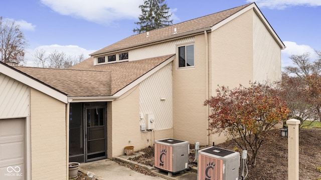 back of property with central air condition unit and a garage