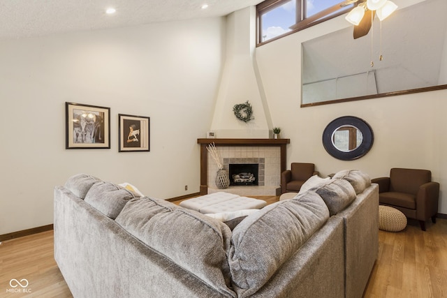 living room with light wood-type flooring, lofted ceiling, a textured ceiling, and a tile fireplace