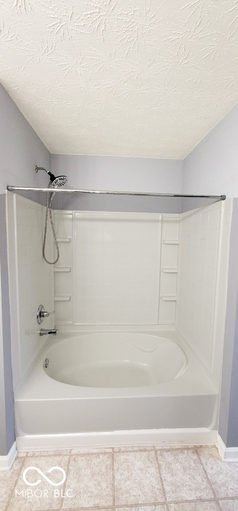 bathroom featuring tile patterned floors, a textured ceiling, and bathtub / shower combination