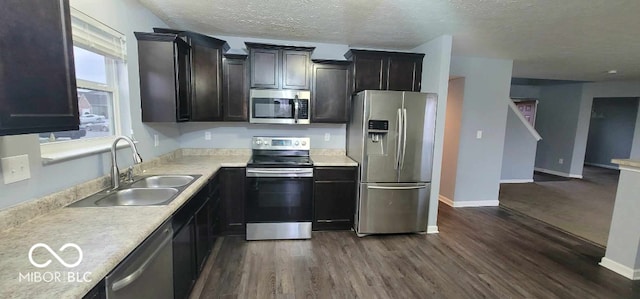 kitchen featuring a textured ceiling, sink, stainless steel appliances, and dark wood-type flooring