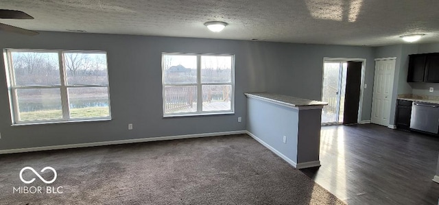 interior space featuring dishwasher, kitchen peninsula, a textured ceiling, and dark wood-type flooring