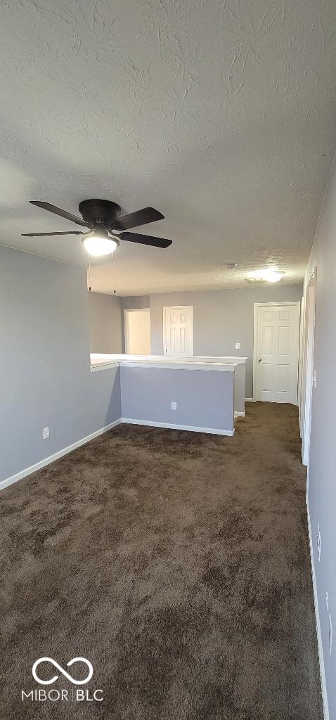 empty room with dark carpet and a textured ceiling