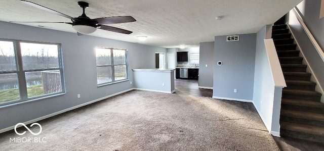 unfurnished living room featuring dark colored carpet, ceiling fan, and a textured ceiling