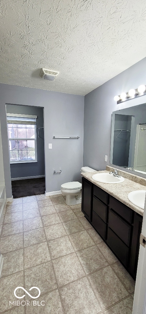 bathroom featuring tile patterned floors, vanity, toilet, and a textured ceiling