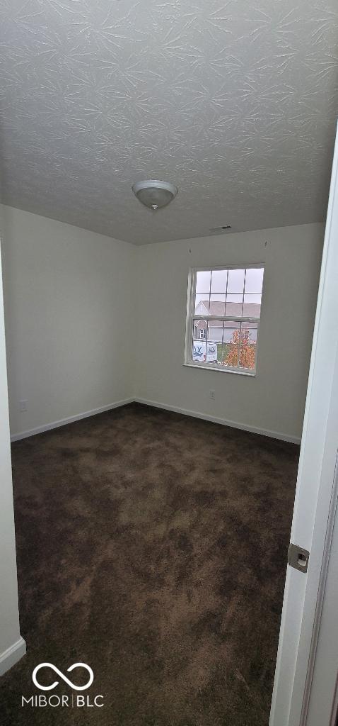 carpeted empty room featuring a textured ceiling