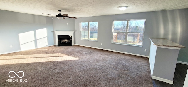 unfurnished living room with ceiling fan, carpet, and a textured ceiling