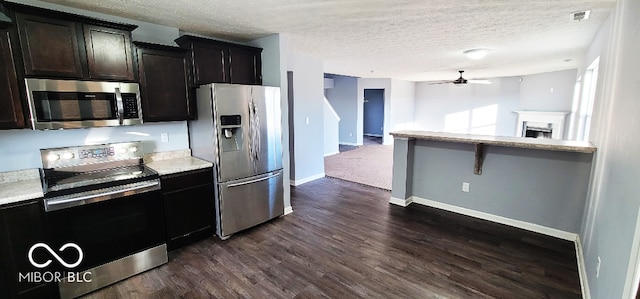 kitchen with dark wood-type flooring, ceiling fan, a textured ceiling, appliances with stainless steel finishes, and dark brown cabinets