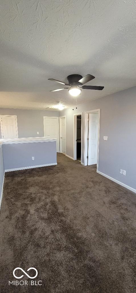 spare room with dark carpet and a textured ceiling