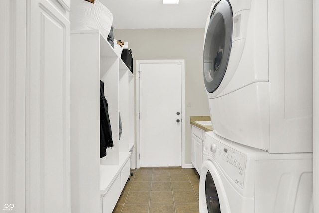 laundry area with cabinets, tile patterned floors, and stacked washer / dryer