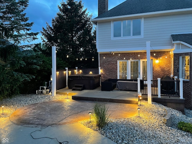 back house at dusk with a patio area and a hot tub