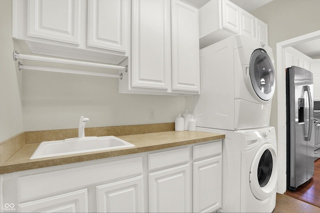 clothes washing area with dark hardwood / wood-style flooring, stacked washing maching and dryer, and sink