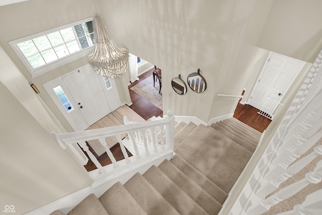 entrance foyer featuring hardwood / wood-style floors, a towering ceiling, and a notable chandelier