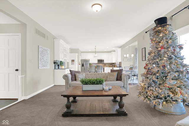 living room with a notable chandelier and dark colored carpet