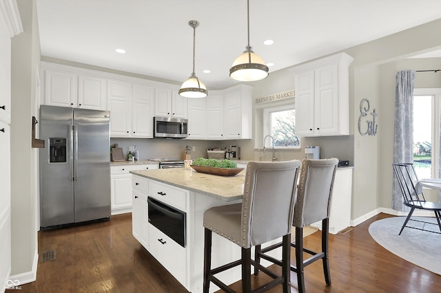 kitchen featuring white cabinets, appliances with stainless steel finishes, and a wealth of natural light