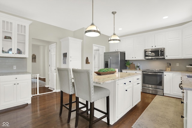 kitchen featuring white cabinetry, stainless steel appliances, dark hardwood / wood-style floors, decorative light fixtures, and a kitchen island