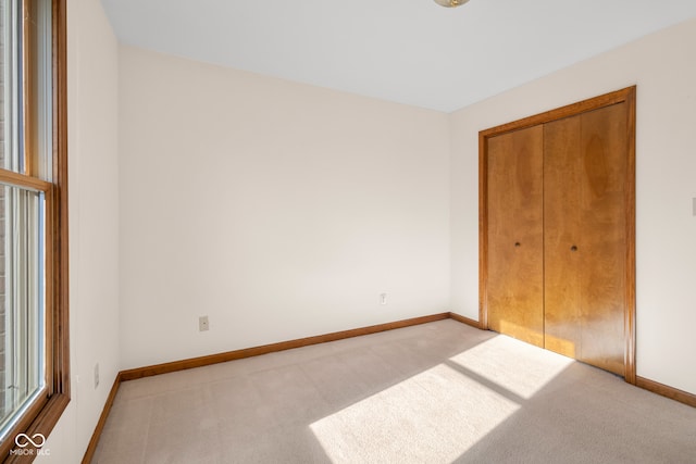 unfurnished bedroom featuring a closet and light colored carpet