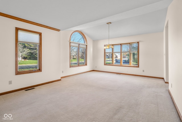 spare room featuring light carpet, vaulted ceiling, a wealth of natural light, and a notable chandelier