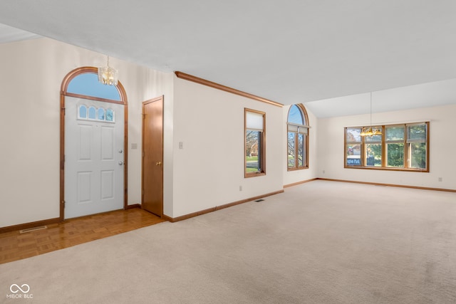 carpeted entryway with a wealth of natural light, crown molding, and a chandelier