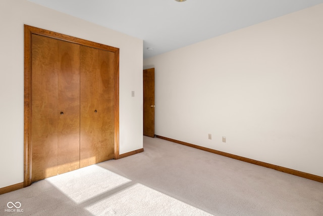 unfurnished bedroom featuring light carpet and a closet